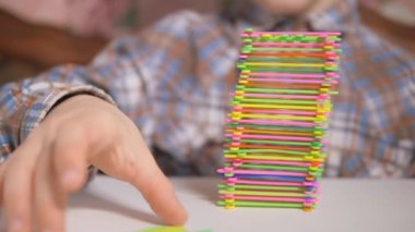 Çocuk renkli çubuklardan bir piramit inşa ediyor. Tablo oyunları.