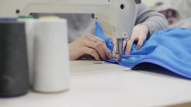 Naaiatelier. Vrouw die naait op een industriële naaimachine. Handen van dichtbij. Plaats een rits in het product. — Stockvideo