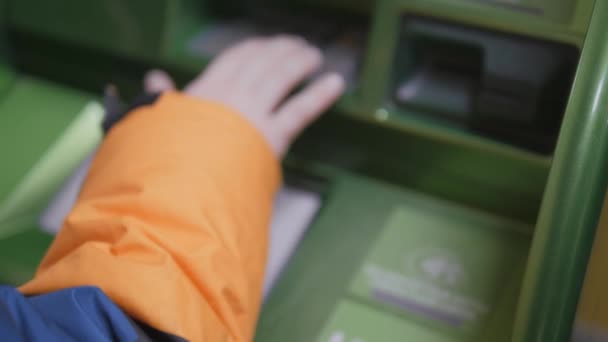 Geld opnemen bij een geldautomaat. Het kind neemt geld op uit de geldautomaat. Defocatie. — Stockvideo