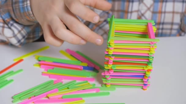 소년은 색깔있는 막대기로 피라미드를 만든다. 테이블 게임. — 비디오