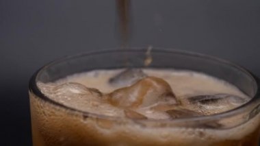 Buzlu bardak soda ile doludur. Buzlu koyu karbonatlı içecekler..