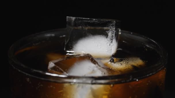 Vidro de gelo é preenchido com água com gás. Derramando bebidas carbonatadas escuras com cubos de gelo. — Vídeo de Stock