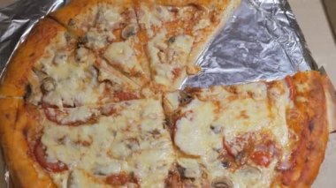 Kutunun içinde peynirli büyük yuvarlak pizza. Fırın parçalarının dağıtımı. PIZZA