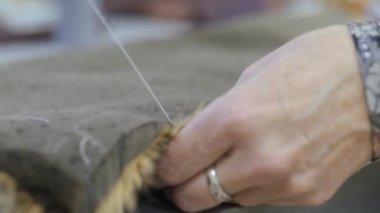 Dikiş atölyesi. Elle iki parça sahte kürk dikiyorum. İğne iplikle dikmek.