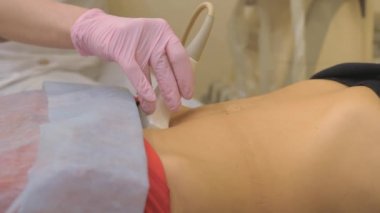 Sağlık kontrolleri. Ultrason cihazı üzerinde çalış, ultrason muayenesi. Sensör karın boyunca hareket ediyor..