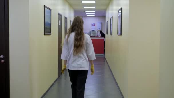 Un operatore medico in una tuta medica passa attraverso il corridoio della clinica. — Video Stock
