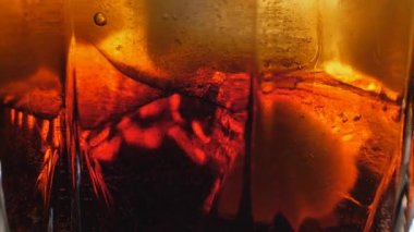 Yakından buz küpleriyle kola dolduruyorum. Buzlu kola ve camda kabarcıklar..