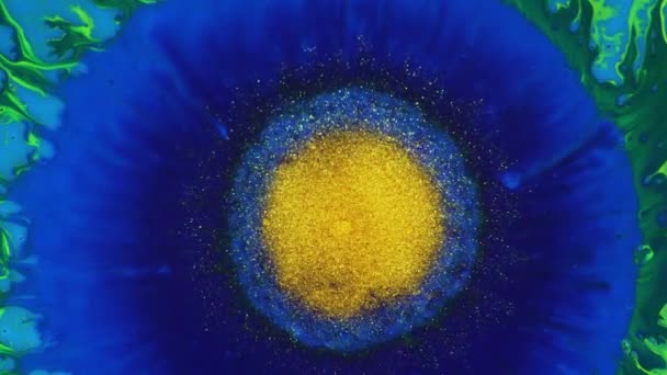 Bright yellow spot, a drop of paint, sprouts on a blue background. Gold dust erupts, boils. — Stock Video