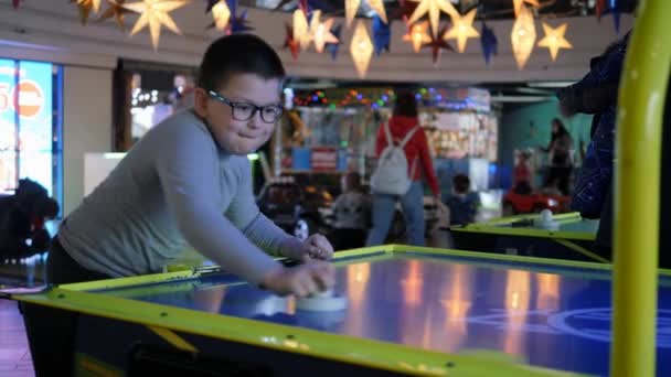 Air hockey. The boy enthusiastically plays a board game entertaining outdoor game. — Stock Video