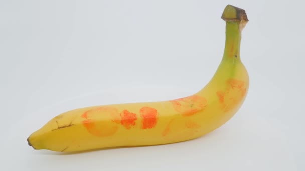 Een banaan op een witte achtergrond. Sporen van lippenstift op de huid van een banaan. — Stockvideo