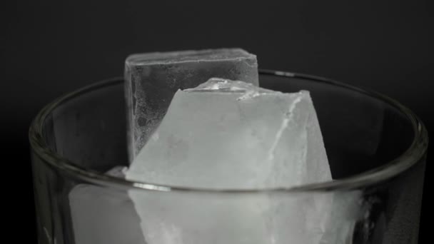 Cubos de hielo en un vaso sobre un fondo negro. — Vídeo de stock