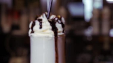 Büyük bardakta kremalı milkshake. Tatlı şurup damlaları kadehten damlıyor..