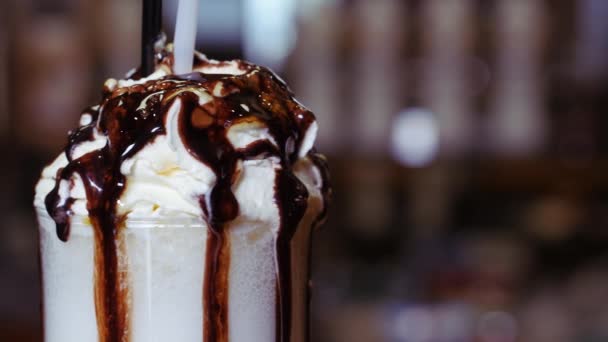 Milkshake met slagroom in een groot glas. Zoete druppels siroop druppelen door het glas. — Stockvideo