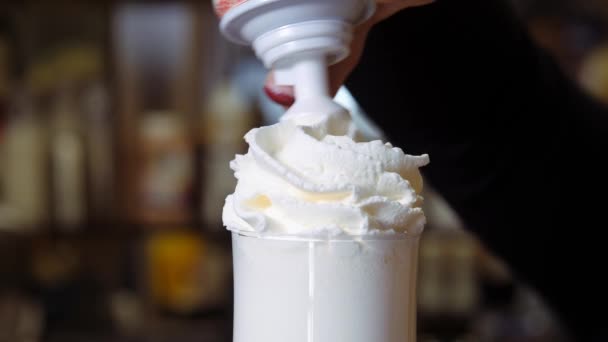 Milkshake com chantilly em um copo alto. Decoração com cobertura de chocolate e tubos de coquetel. — Vídeo de Stock