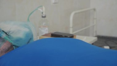 Hastane yatağında hasta bir adam. Koluna damar içi damlalar yerleştirildi. Oksijen maskesinin yüzünde. Oksijen zengini solunum.