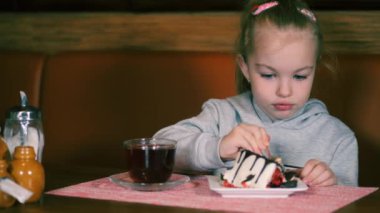 Küçük kız taze çilek ile tatlı yer ve çay içer. Çocuk yemek yerken tatlı tatlı gülümser..