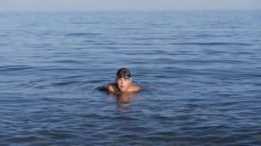 Koyu saçlı, bronz tenli çocuk deniz suyu sıçratıyor..