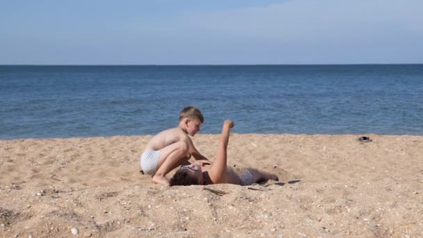 Los niños en la playa de arena de mar juegan con arena. — Vídeos de Stock