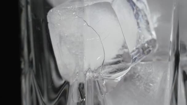 Primer plano de un vaso de vidrio con agua. Trozos de hielo derretidos. — Vídeo de stock