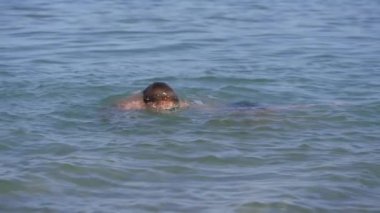 Bronzlaşmış çocuk deniz suyu sıçratıyor. Çocukların duyguları..