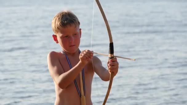 Junge am Strand lädt Pfeile in einen Bogen. — Stockvideo