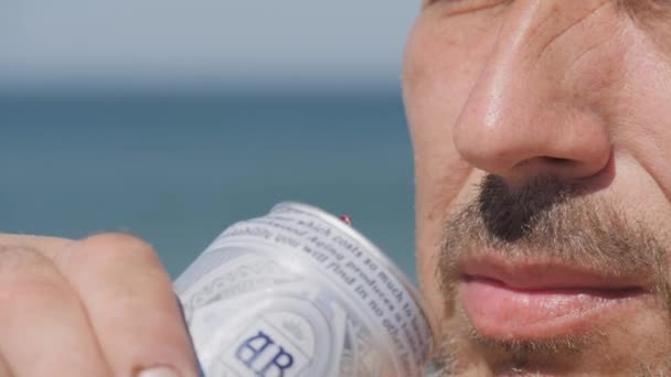 09 septembre 2020, Crimée, Mer d'Azov, village de Zolotoe-rédaction-Bière BUD. Une boîte en métal est apportée aux lèvres mâles entourées d'une barbe et d'une moustache. L'homme boit. — Video