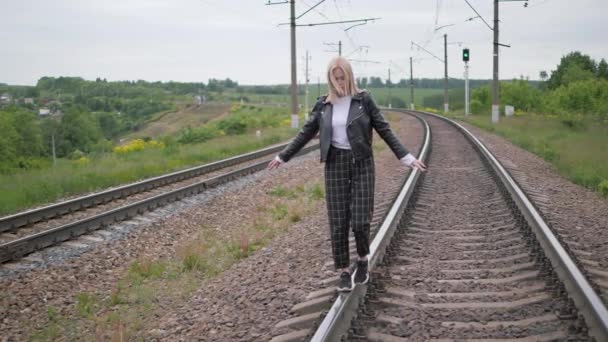 Young woman walks on the rail of the railway tracks. — Stock Video