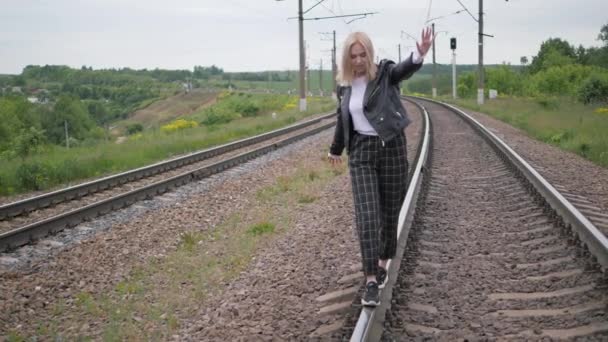 Young woman walks on the rail of the railway tracks. — Stock Video