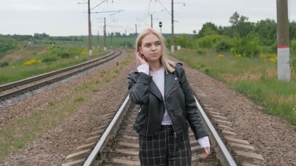 Young woman walks on the rail of the railway tracks. — Stock Video