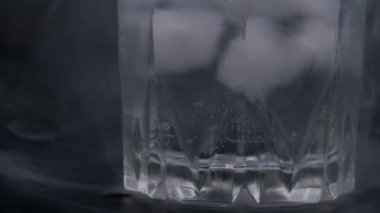 Siyah arka planda buzlu bir bardak. Maden suyunda kabarcıklar. Dumanla dolu.