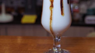 Büyük bardakta kremalı milkshake. Tatlı şurup damlaları kadehten damlıyor..