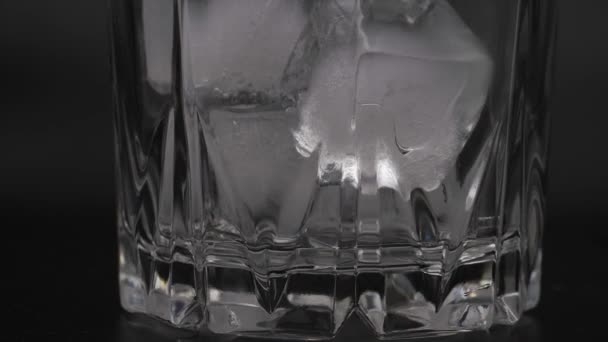 Cubi di ghiaccio in un bicchiere su sfondo nero. — Video Stock