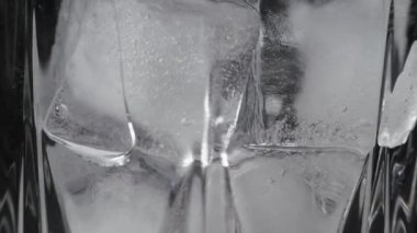 Bardağı suyla yakın plan çek. Buz parçaları eriyor.