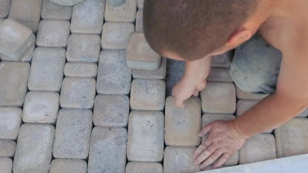 Byggnadsarbeten. Lägga gatstenar, stenar på gågatan i ett hus på landet. Installation av trottoaren. — Stockvideo