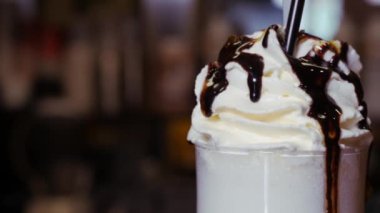 Büyük bardakta kremalı milkshake. Tatlı şurup damlaları kadehten damlıyor..