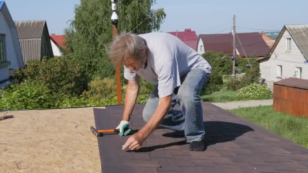 Dakbedekking. Bevestiging met spijkers en een hamer van het dakmateriaal. De camera kijkt naar het werk van installateurs. — Stockvideo