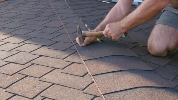 Travaux de toiture. Pose d'un élément de tuile souple sur la crête du toit et son installation. Installation du toit à la base. — Video