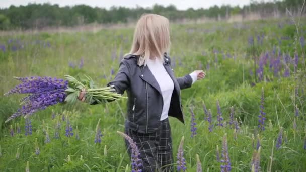 Młoda dziewczyna wiruje na polu. Kobieta delikatnie obejmuje bukiet kwiatów. — Wideo stockowe