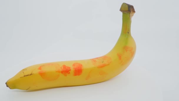 Jeden banan na białym tle. Ślady szminki na skórze banana. — Wideo stockowe