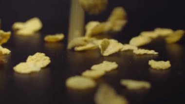 Siyah arka planda düşen mısır gevrekleri.