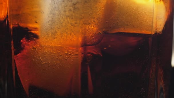 Cola gieten met ijsblokjes van dichtbij. Cola met ijs en belletjes in glas. — Stockvideo