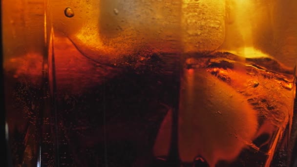 Cola in Großaufnahme mit Eiswürfeln übergießen. Cola mit Eis und Blasen im Glas. — Stockvideo