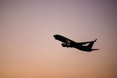 Silhouette flying plane while sunset clipart