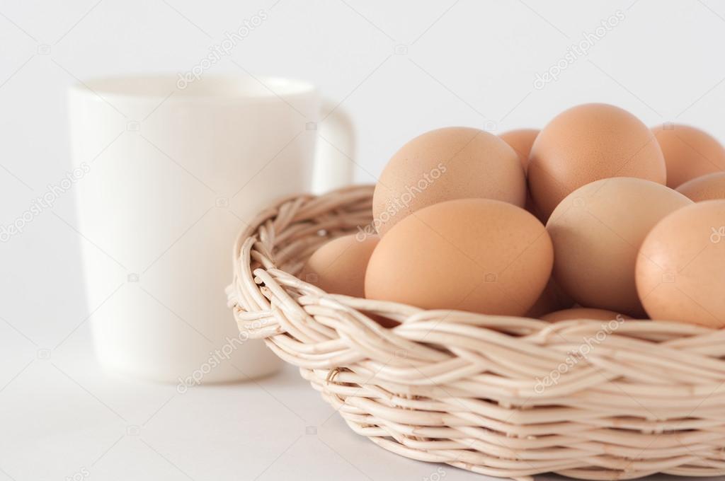 Eggs in the brown basket and a cup of milk