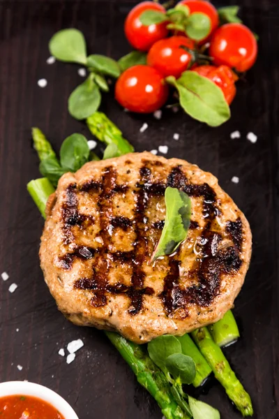 Costeleta de carne grelhada que serve com espargos e tomates — Fotografia de Stock