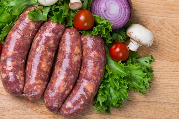 Saucisses crues crues non cuites sur planche de bois — Photo