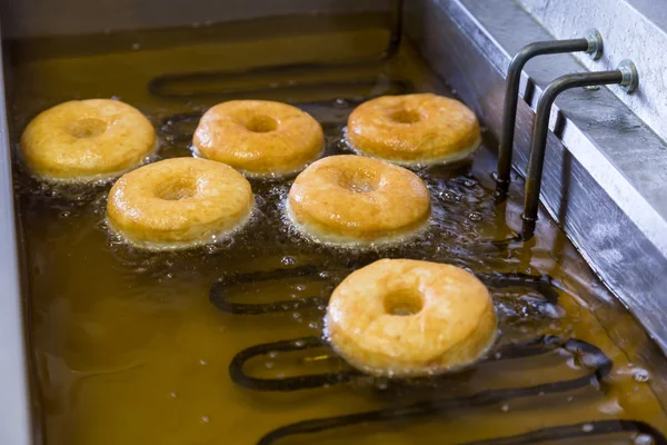 Gebakken gelijke ronde donuts in friteuse — Stockfoto