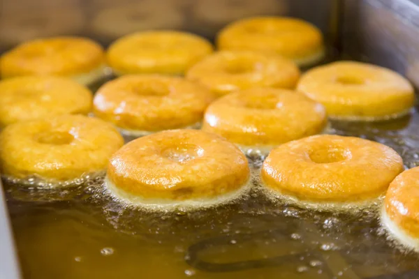 Donuts redondos iguais fritos em fritadeira — Fotografia de Stock