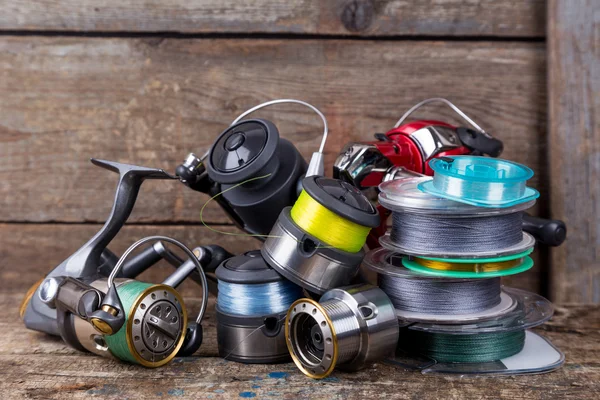 Fishing reels and spoole with line on wooden background — Stock Photo, Image
