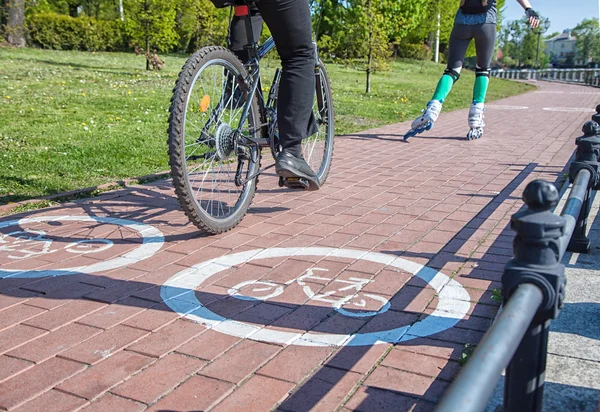 Menina de patinação e bicicleta no caminho da bicicleta — Fotografia de Stock